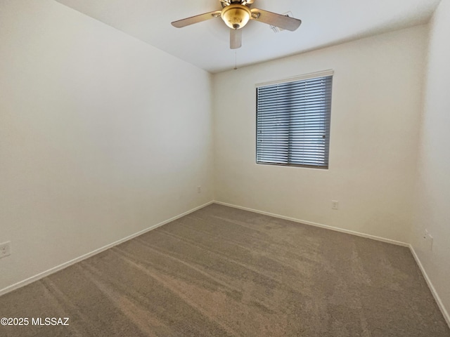 carpeted spare room with ceiling fan and baseboards