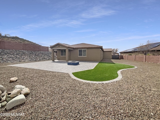 rear view of property with a patio area, a tile roof, a fenced backyard, and stucco siding