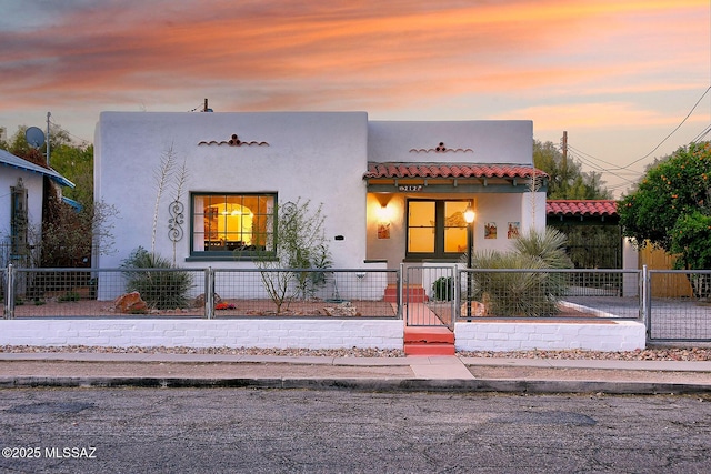 view of front of house featuring a fenced front yard, a tiled roof, and stucco siding