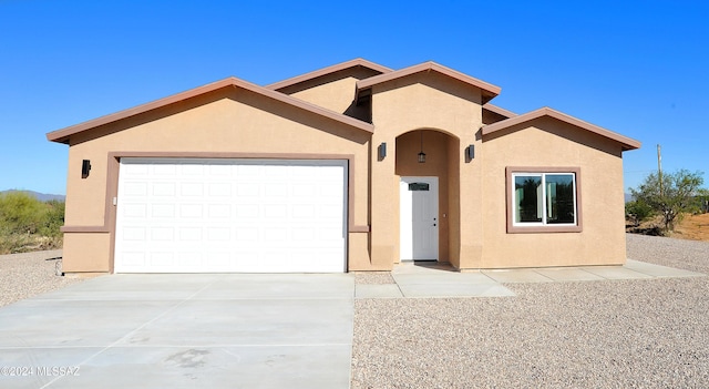 view of front of home with driveway, an attached garage, and stucco siding