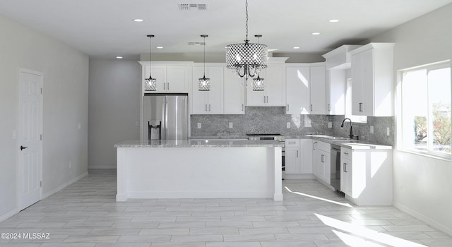 kitchen featuring visible vents, backsplash, appliances with stainless steel finishes, white cabinetry, and a kitchen island