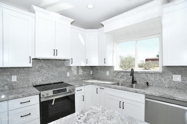 kitchen with appliances with stainless steel finishes, a sink, white cabinetry, and decorative backsplash