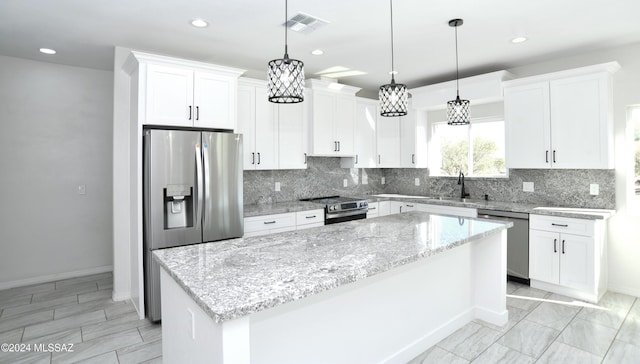 kitchen with a kitchen island, visible vents, white cabinets, appliances with stainless steel finishes, and decorative backsplash