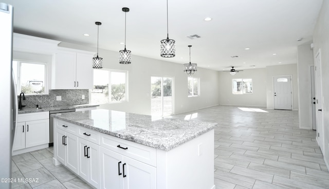 kitchen with tasteful backsplash, visible vents, dishwasher, decorative light fixtures, and a center island