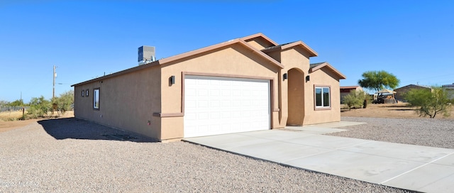 view of home's exterior with a garage, concrete driveway, central AC, and stucco siding