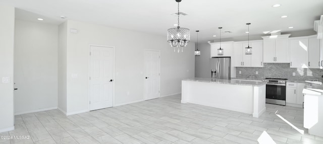 kitchen with a kitchen island, an inviting chandelier, stainless steel appliances, white cabinetry, and backsplash