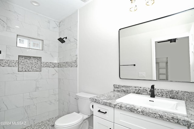 full bathroom featuring toilet, a tile shower, and vanity