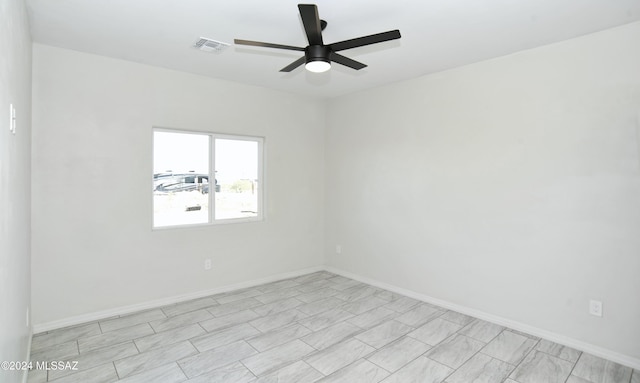 spare room featuring ceiling fan, visible vents, and baseboards