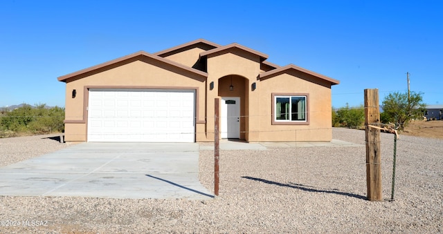 view of front of house with concrete driveway, an attached garage, and stucco siding