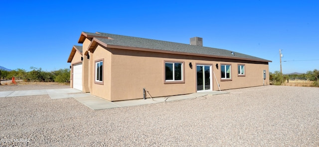 rear view of house with a chimney and stucco siding