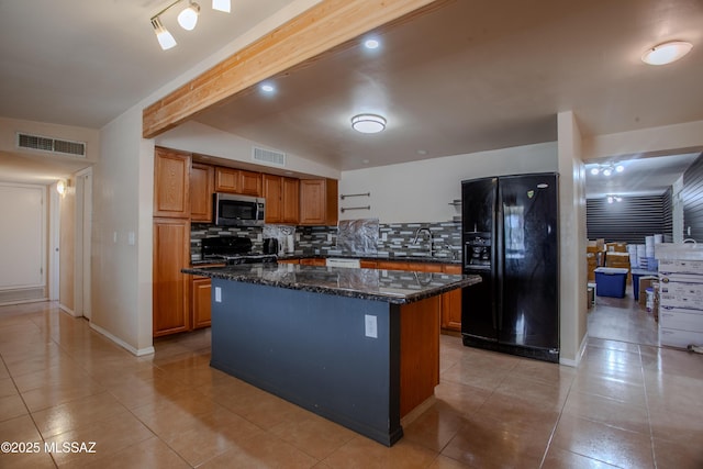 kitchen featuring stainless steel microwave, black refrigerator with ice dispenser, visible vents, and a sink