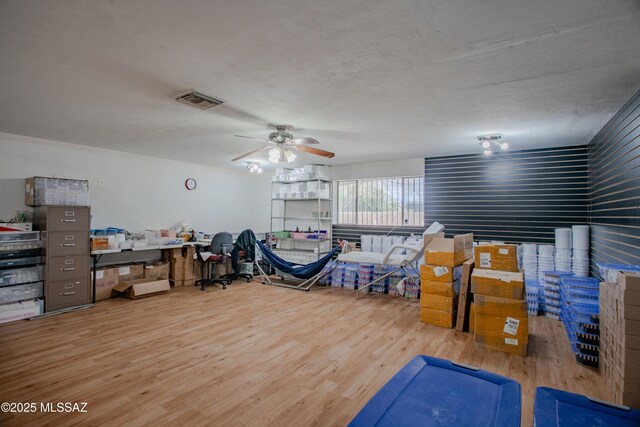 interior space featuring a textured ceiling, wood finished floors, visible vents, and a ceiling fan