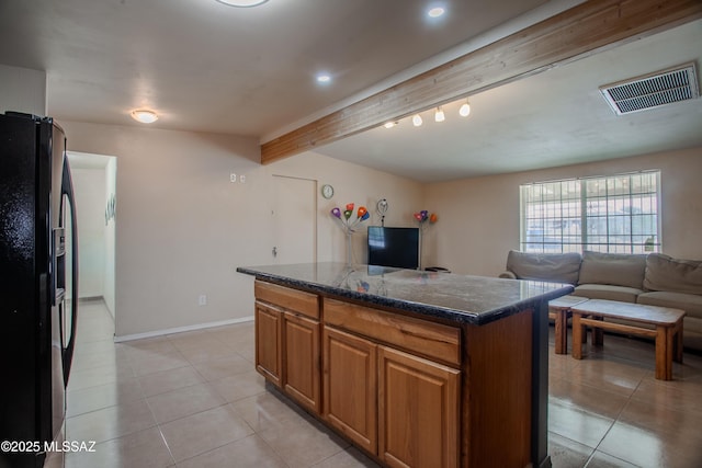 kitchen featuring light tile patterned floors, visible vents, black fridge with ice dispenser, a kitchen island, and beamed ceiling