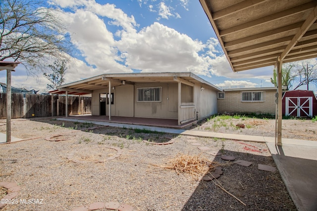 view of front of house with a storage unit, fence, an outdoor structure, a patio area, and brick siding