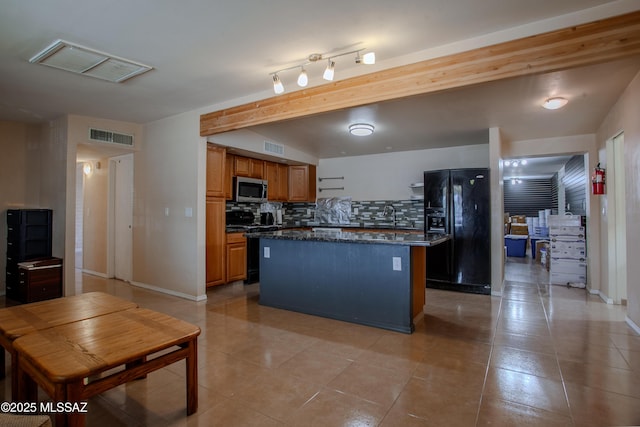 kitchen featuring stainless steel microwave, visible vents, black refrigerator with ice dispenser, gas range oven, and tasteful backsplash