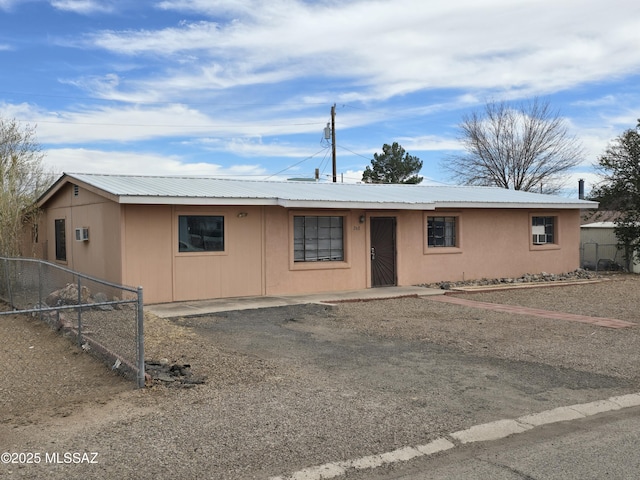 ranch-style home with metal roof and fence