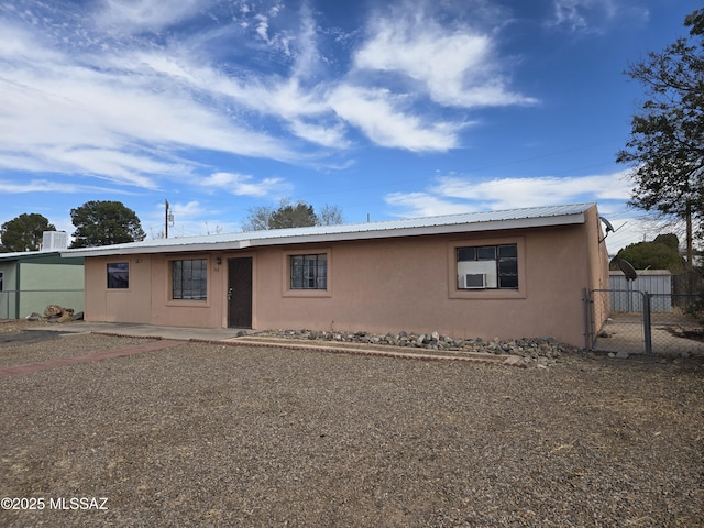 view of front of property with metal roof, fence, a gate, and stucco siding