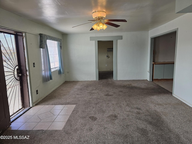 unfurnished living room with carpet, tile patterned flooring, and ceiling fan