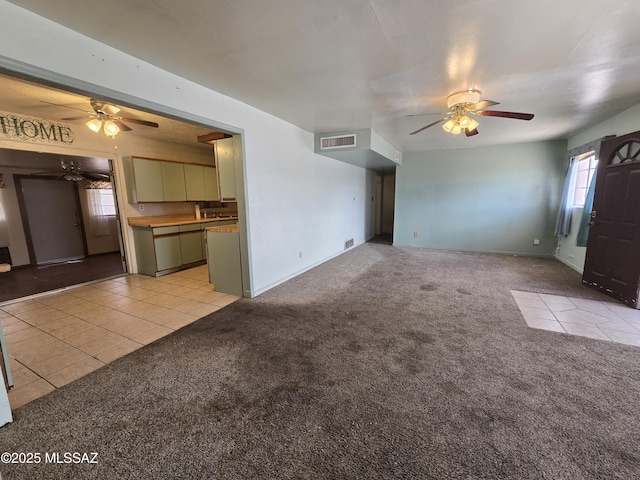 unfurnished living room featuring light carpet, ceiling fan, light tile patterned floors, and visible vents