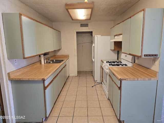 kitchen featuring light countertops, visible vents, a sink, white appliances, and under cabinet range hood