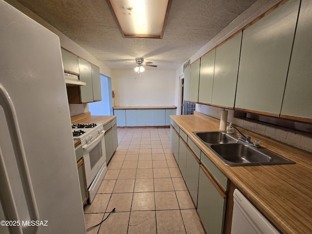 kitchen featuring white appliances, light tile patterned floors, wainscoting, under cabinet range hood, and a sink