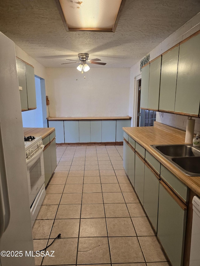 kitchen featuring light tile patterned floors, ceiling fan, a sink, a textured ceiling, and white appliances