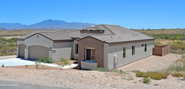 view of front of house featuring a tile roof, stucco siding, concrete driveway, a mountain view, and a garage