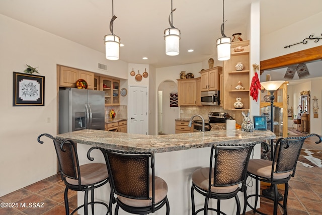 kitchen with visible vents, light brown cabinetry, tasteful backsplash, stainless steel appliances, and arched walkways