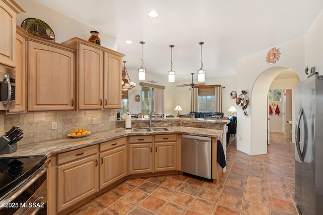 kitchen with light brown cabinetry, appliances with stainless steel finishes, a peninsula, and a sink