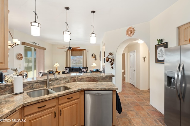 kitchen featuring light brown cabinets, appliances with stainless steel finishes, light stone counters, and a sink