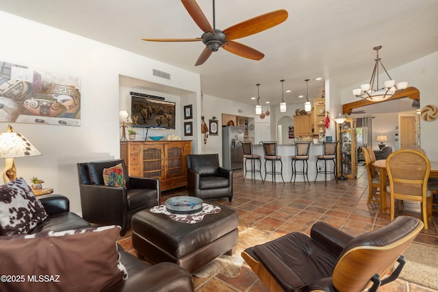 tiled living area featuring recessed lighting, visible vents, arched walkways, and ceiling fan with notable chandelier