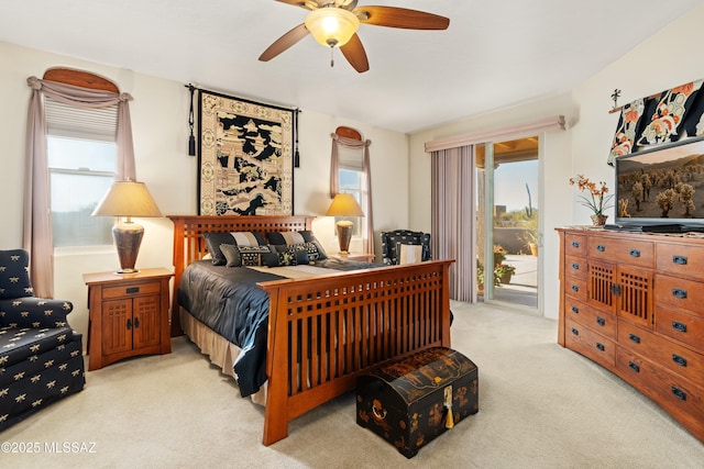 bedroom with access to exterior, light colored carpet, a ceiling fan, and multiple windows