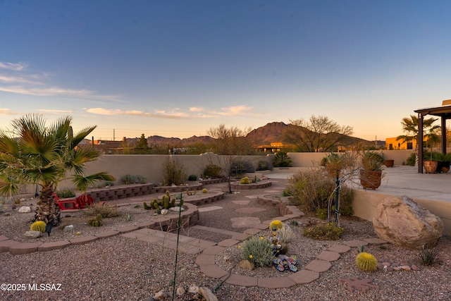 yard at dusk with a fenced backyard and a patio area