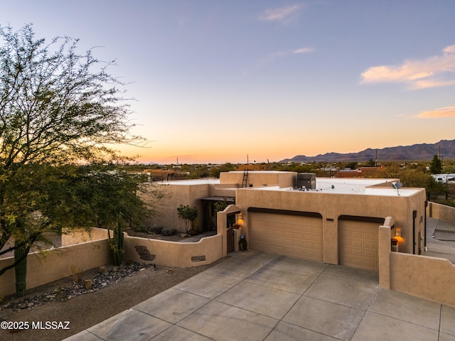 southwest-style home with stucco siding, fence, a mountain view, concrete driveway, and an attached garage