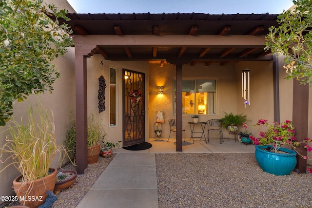 doorway to property with stucco siding and covered porch