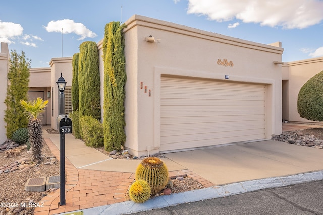 view of front of house with driveway, an attached garage, and stucco siding