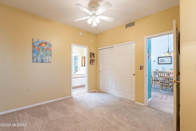 unfurnished bedroom with baseboards, visible vents, connected bathroom, light colored carpet, and a closet