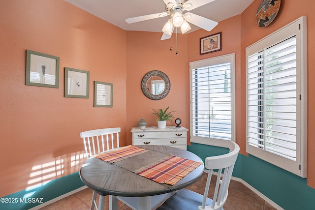 dining area featuring tile patterned flooring, a ceiling fan, and baseboards