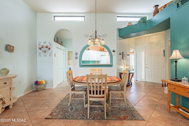 dining area featuring light tile patterned floors, arched walkways, visible vents, a towering ceiling, and an inviting chandelier