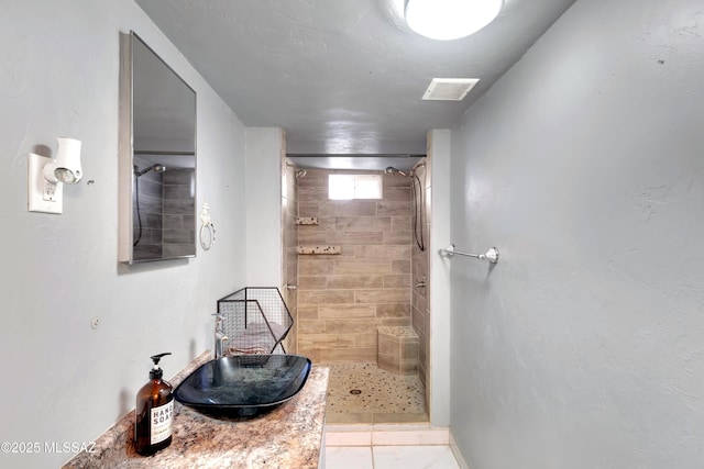 bathroom featuring a tile shower, visible vents, and a sink