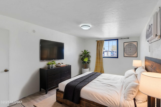 bedroom with a textured ceiling and light wood-style flooring