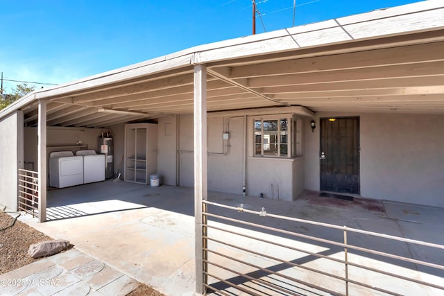 view of parking / parking lot featuring a carport, electric water heater, concrete driveway, and washer and clothes dryer