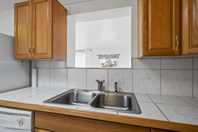 kitchen featuring dishwasher, backsplash, a sink, and brown cabinets