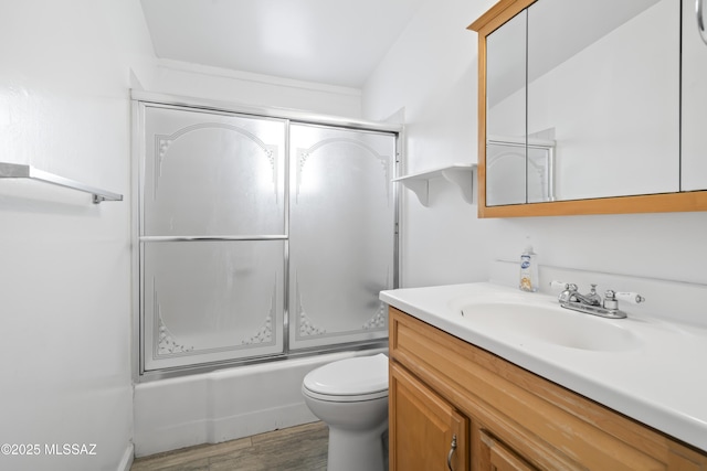 bathroom with toilet, bath / shower combo with glass door, wood finished floors, and vanity