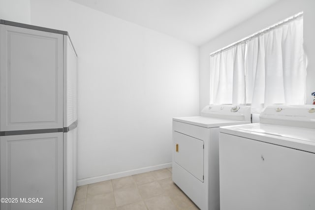 clothes washing area with laundry area, washing machine and dryer, light tile patterned floors, and baseboards