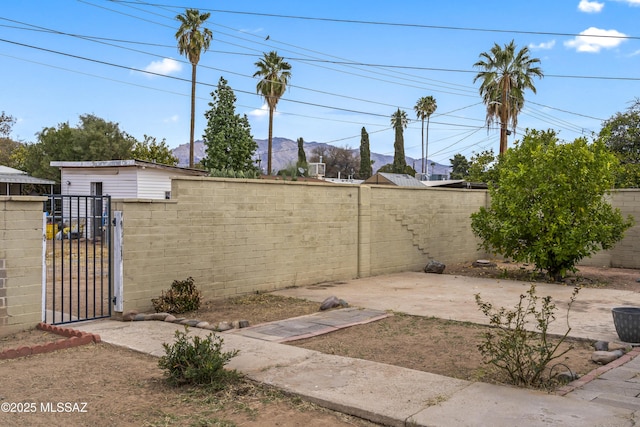 view of yard with a patio, a fenced backyard, and a gate