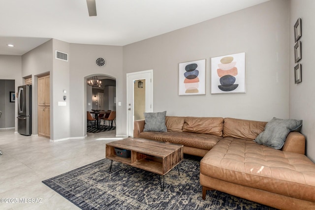 living room with arched walkways, lofted ceiling, a ceiling fan, visible vents, and baseboards