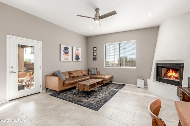 living area with a ceiling fan, a fireplace, light tile patterned flooring, and a healthy amount of sunlight