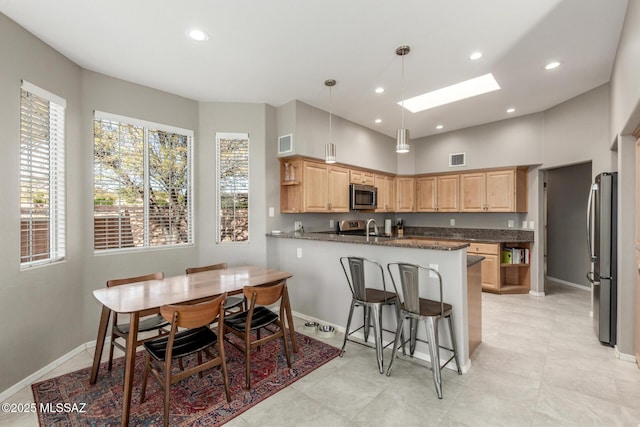 kitchen featuring a skylight, open shelves, appliances with stainless steel finishes, light brown cabinets, and a peninsula