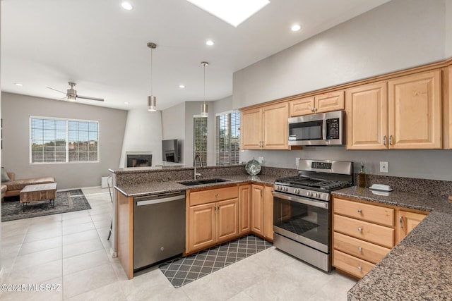 kitchen featuring a peninsula, a sink, open floor plan, appliances with stainless steel finishes, and plenty of natural light